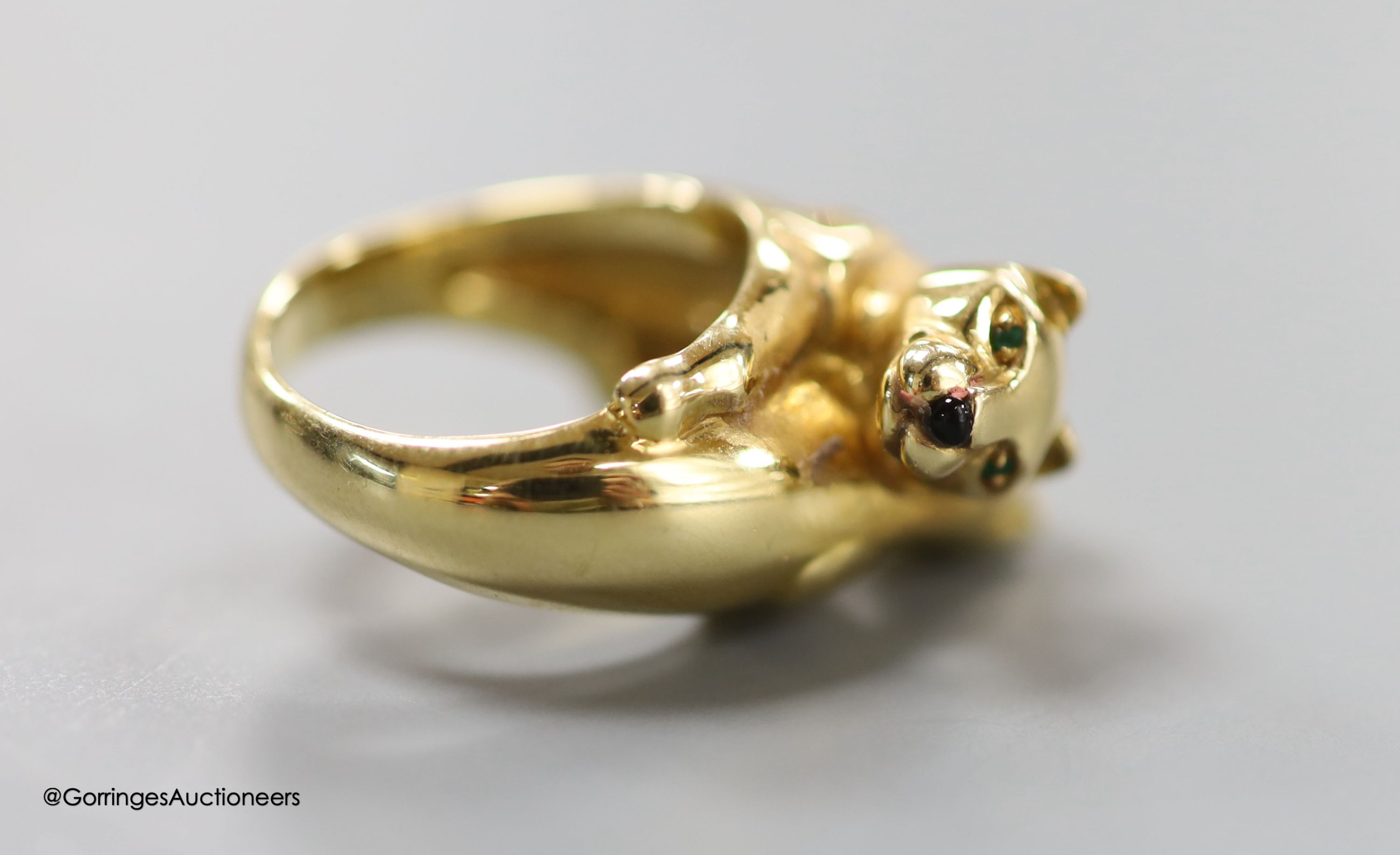 An early 1990's Cartier 18ct gold, black onyx and emerald set twin leopard's head crossover ring